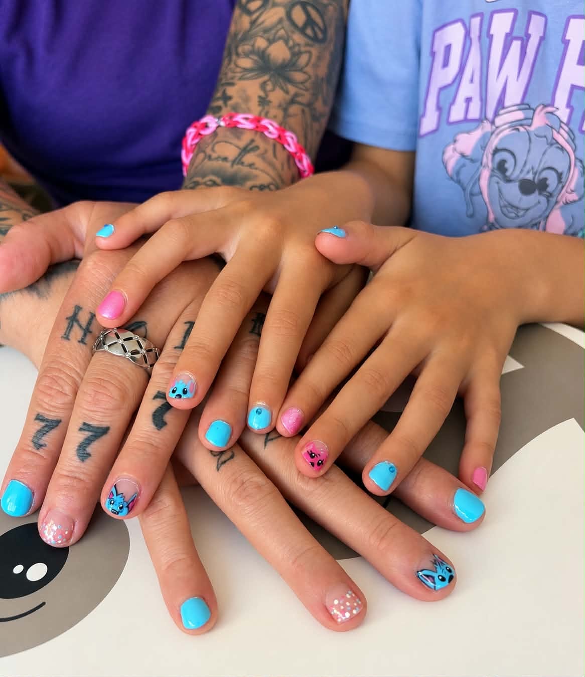 Plusieurs mains aux ongles bleus et roses ornés de petits motifs